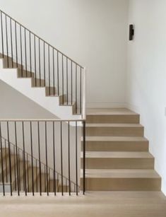 there is a stair case next to the stairs in this house with white walls and wood flooring