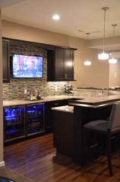 a kitchen with an island, bar and television on the wall in it's center