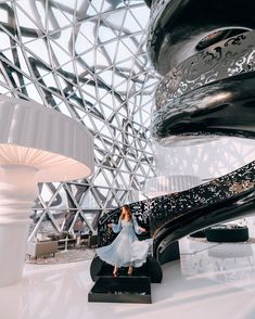 a woman is standing in the middle of a room with large black and white sculptures