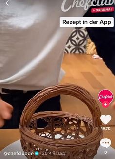 a person holding a basket on top of a wooden table next to a cell phone