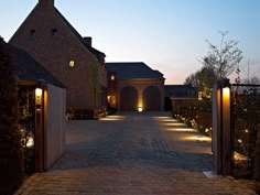 an entrance to a large brick house with lights on the front door and walkway leading into it