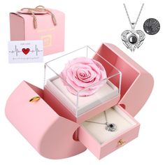 a pink rose in a box with two necklaces