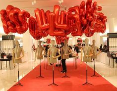 there are many red balloons that spell out the word love in front of mannequins