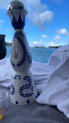 a blue and white vase sitting on top of a towel next to a glass cup