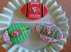 three decorated cookies sitting on top of a white plate covered in sprinkles