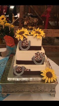 a three tiered cake with sunflowers on the top is sitting on a table