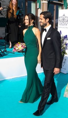 a man and woman in formal wear walking on the blue carpet