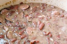 a pot filled with beans and sausages on top of a stove