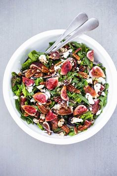 a white bowl filled with salad topped with figs and goat cheese next to a fork