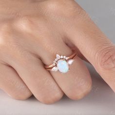 a woman's hand with a white opal and diamond ring on her finger