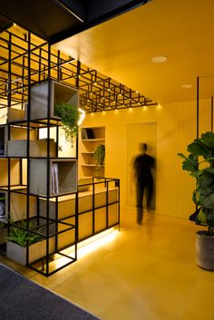 a man is standing in the middle of a room with shelves and plants on it