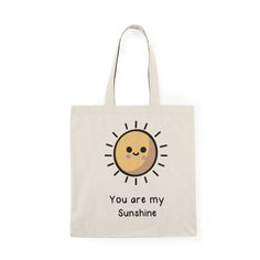 Brighten up your day and carry a ray of positivity wherever you go with our "You Are My Sunshine" tote bag. This cheerful design features a vibrant, smiling cartoon sun, embodying warmth and happiness. It's the perfect accessory to remind you or a loved one of the light they bring into the world. Product Features: Size and Material: Measuring 40 x 38 cm (15.7 x 15 inches), the tote is crafted from 100% recycled cotton, making it an eco-friendly choice that doesn't sacrifice style or durability. Fun Cotton Canvas Bag For Everyday, Cartoon Sun, Sun Design, Sun Designs, You Are, Uplifting Messages, Beach Essentials, Gift For Music Lover, My Sunshine