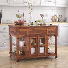 a wooden kitchen island with glass doors and drawers