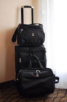 three pieces of luggage are stacked on top of each other in front of a window