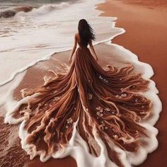 a woman is standing on the beach with her dress flowing in the wind and water