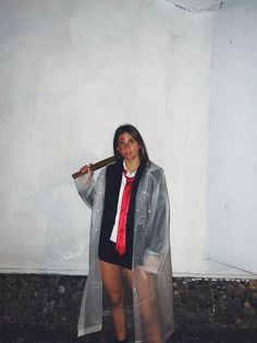 a woman in a raincoat holding a baseball bat and posing for the camera with red paint on her face