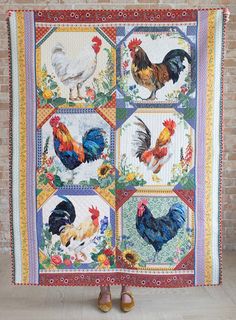 a woman standing in front of a quilt with roosters on it's sides