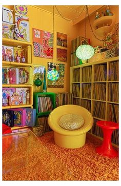 a room filled with lots of records on shelves and colorful chairs in front of them