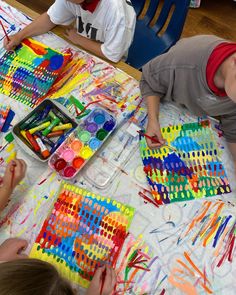 two boys sitting at a table with art supplies