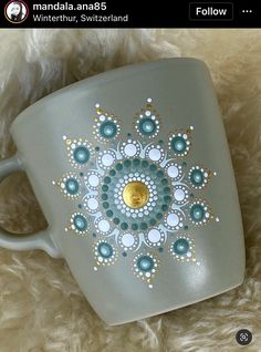 a coffee cup with an intricate design painted on the side and gold in the middle