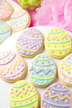 decorated cookies are on a plate next to tissue pom poms and streamers