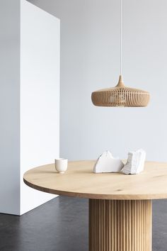 a round wooden table with two white bowls on it and a light hanging from the ceiling