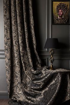 the curtains in this room are drapes with black and gold designs on them, along with a lamp