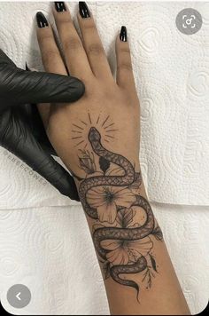 a woman's hand with a tattoo on it and a snake on the wrist