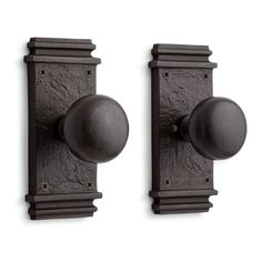 two black door knobs on the side of a wall with an iron ball and finial