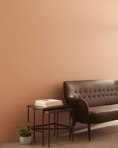 a brown leather couch sitting next to a table with a book on top of it