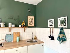 a kitchen with green walls and white tile on the counter top, above a sink