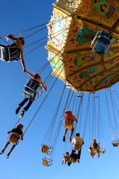 several people are riding on swings in the air at an amusement park or fairground