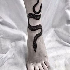 a black and white photo of a person's foot with a snake tattoo on it