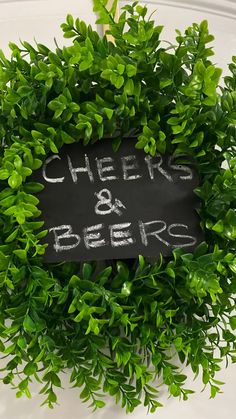 a sign that says cheers and beers is surrounded by greenery in the shape of a wreath