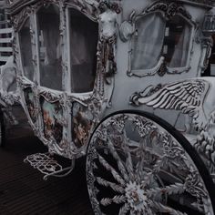 a white horse drawn carriage parked on top of a wooden floor next to other vehicles