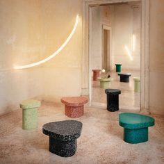 a room filled with different colored stools in front of a white wall and floor