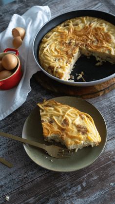 a piece of pie sitting on top of a plate next to an egg in a pan