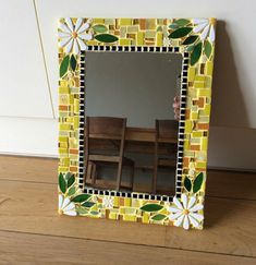 a yellow and green mosaic mirror sitting on top of a wooden floor