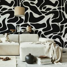 a dog sitting on a couch in front of a wall with black and white designs