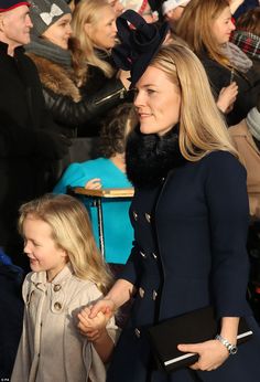 a woman and child walking in front of a crowd