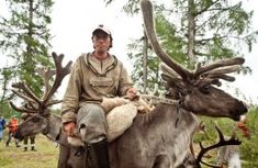 a man riding on the back of an animal with antlers around his neck and head