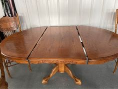 a wooden table with two chairs next to it and a wall in the back ground