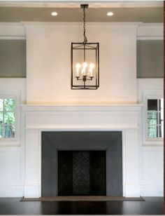 a fire place in a living room with a chandelier hanging from the ceiling