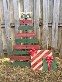 a christmas tree made out of pallet wood and wrapped in red, white and green ribbon