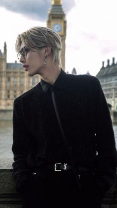 a woman with short hair and glasses standing in front of the big ben clock tower