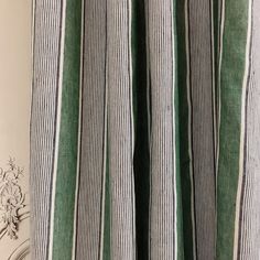 the curtain is striped with green and white stripes, along with an antique clock on the wall behind it