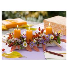 a table topped with candles and flowers on top of a purple cloth covered tablecloth