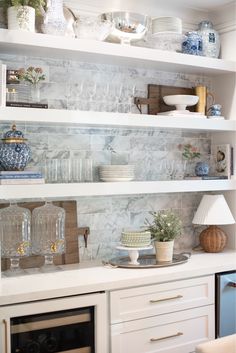 the shelves in this kitchen are filled with dishes and vases