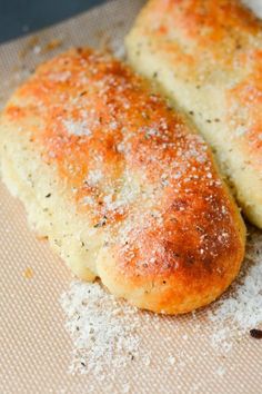 two pieces of bread sitting on top of a piece of wax paper covered in powdered sugar