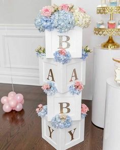 a wooden block tower with flowers and letters on the top, sitting on a table